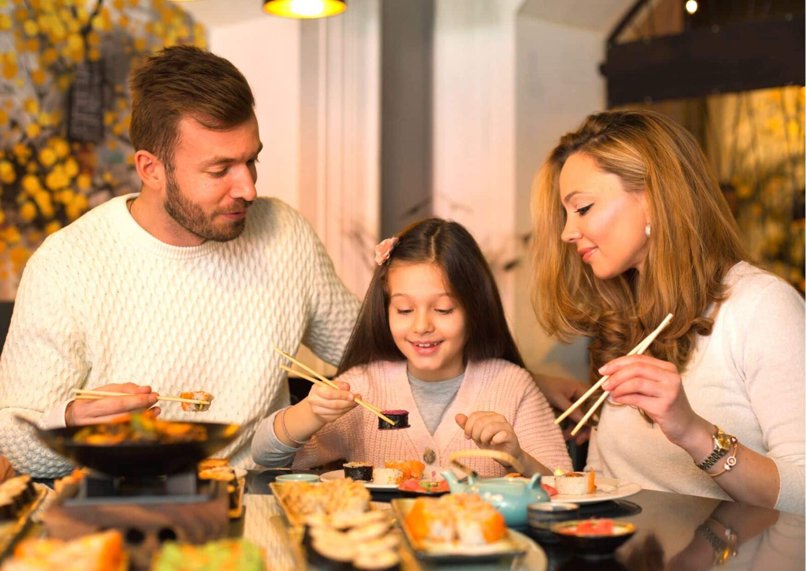 Familie isst mit kleiner Tochter Sushi